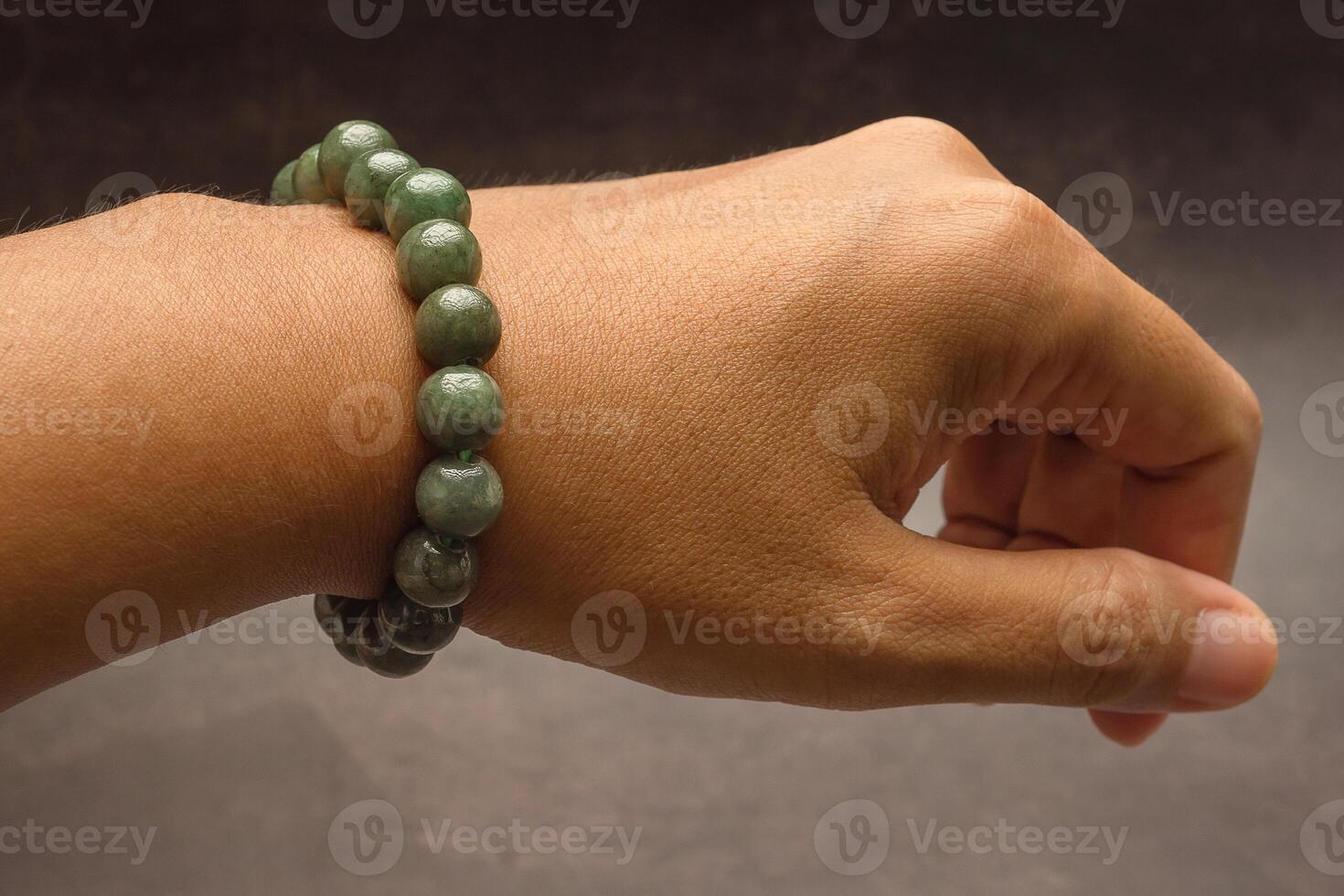 Jade bangle or bracelet on the wrist and a green jade ring on a finger against a black background. Close-up. photo