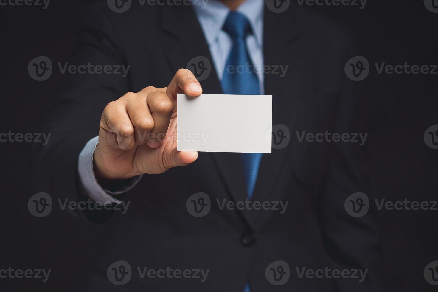 Businessman showing a blank white name card mockup while standing on a black background photo