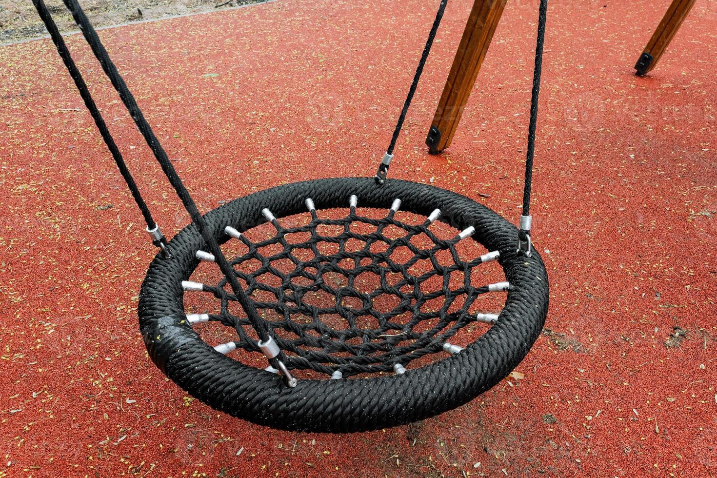 A large and spacious black net swing is currently situated on a bright and vibrant red surface, creating a wonderfully inviting and cheerful atmosphere for outdoor fun and play activities photo