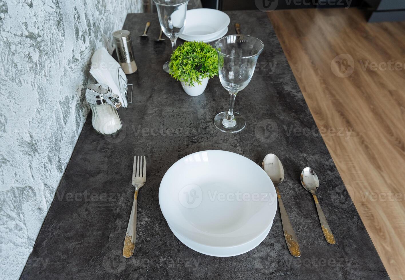 There is a beautifully arranged table featuring plates, silverware, glasses, and a lovely plant placed on it, creating an inviting and warm atmosphere for dining or serving meals photo