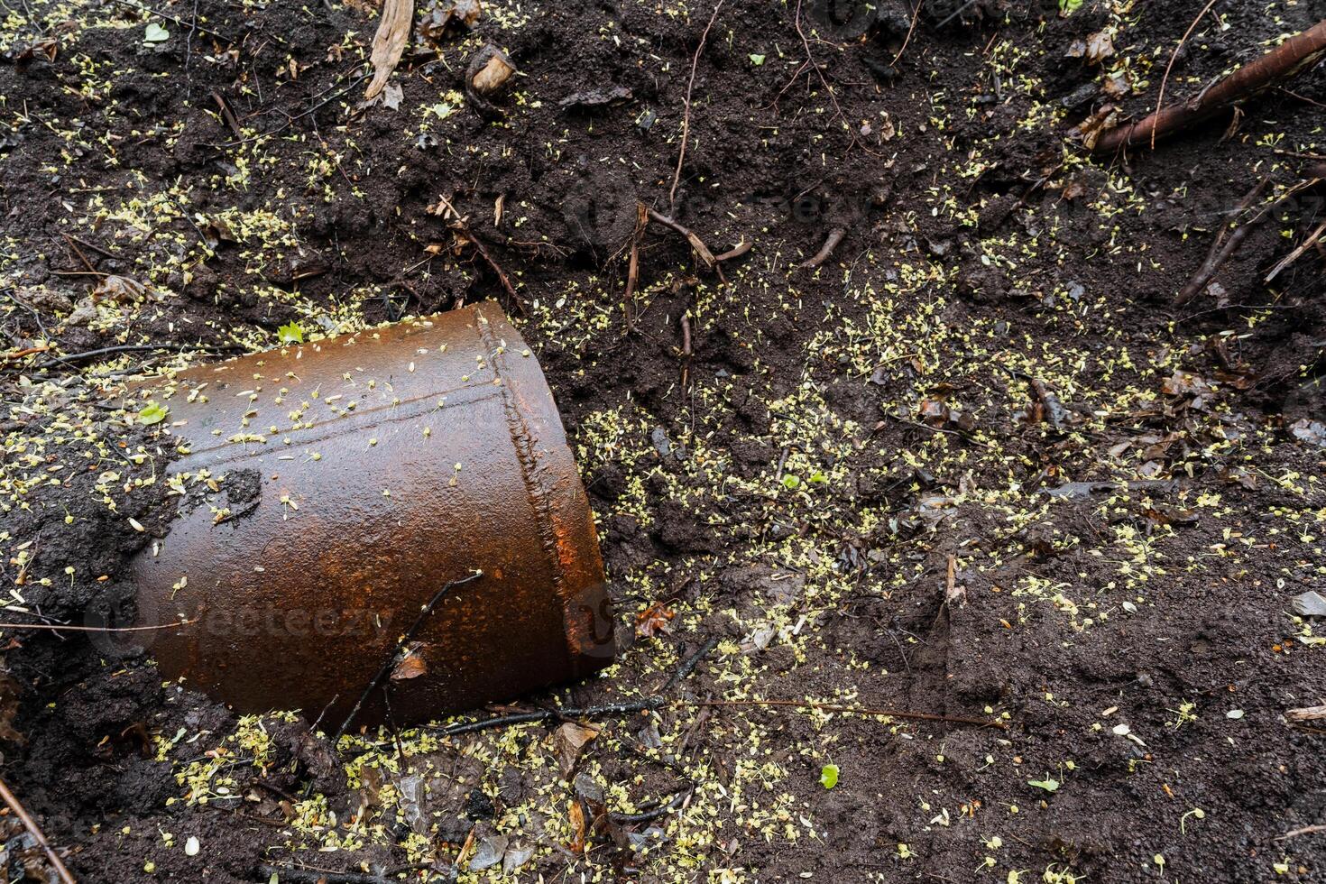 A rusty and grimy old bucket is resting in the dry, parched soil, highlighting the serious and urgent issue of pollution and waste accumulation that is affecting the entire area photo
