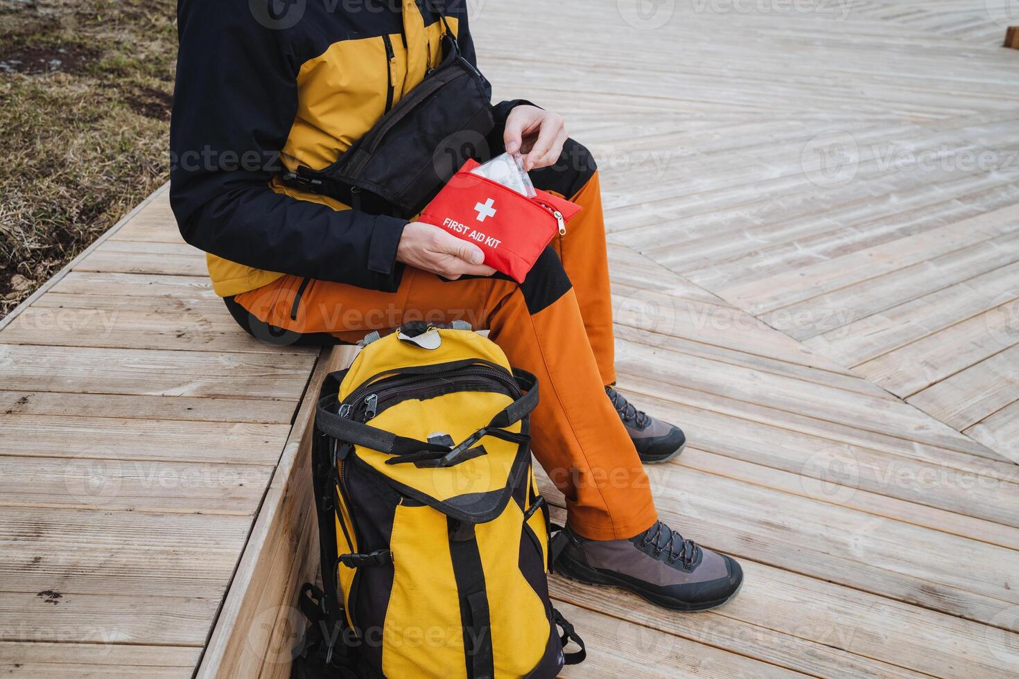 Outdoor Adventure A Hiker Appearing Smartly Equipped with an Essential Emergency Kit While Traveling Along a Beautifully Maintained Wooden Path in Natures Scenic Environment photo