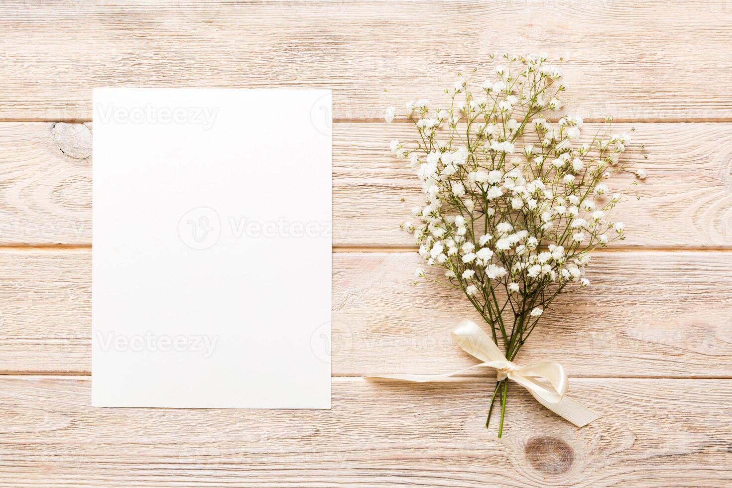 Wedding mockup white paper list and flowers gypsophila on colored table top view flat lay. Blank greeting cards and envelopes. Beautiful floral pattern. Flat lay style photo