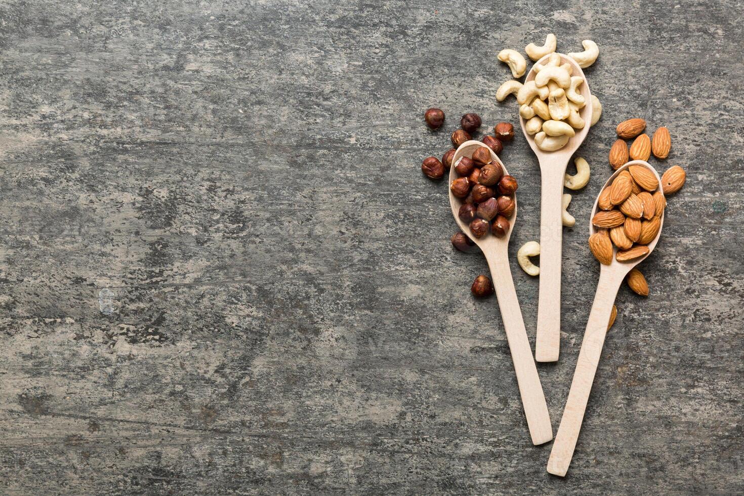 Assortment nuts wooden spoon on colored table. Cashew, hazelnuts, walnuts, almonds. Mix of nuts Top view with copy space photo