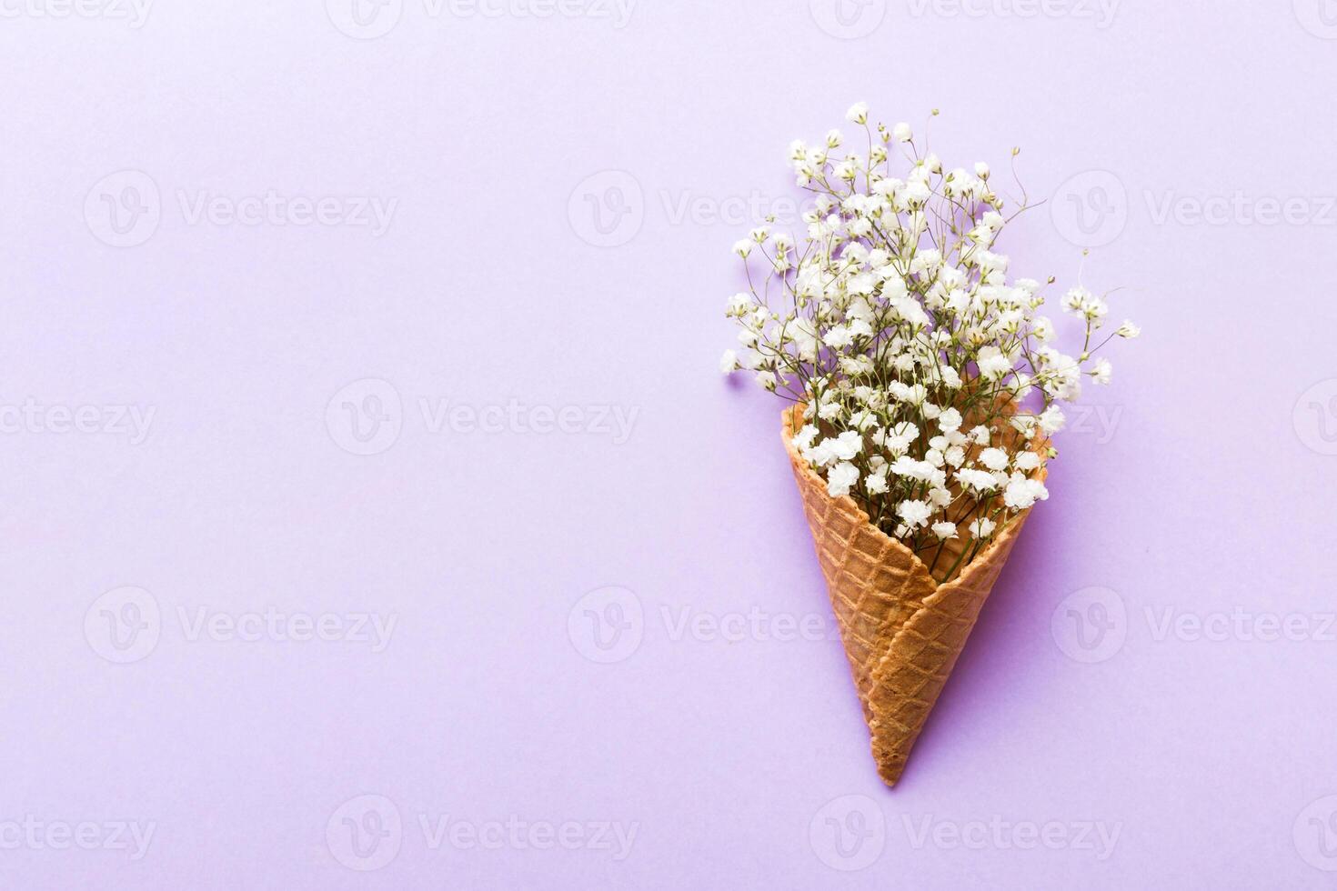 Waffle cone with beautiful gypsophila flowers on color background. summer concept. top view photo