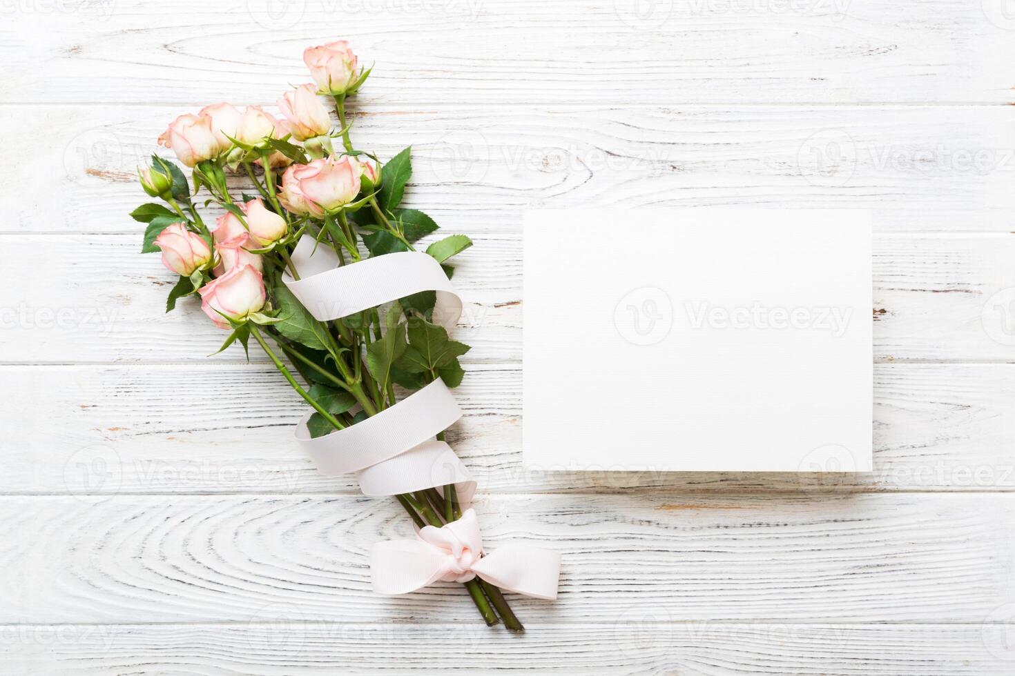 Greeting holiday card mockup with fresh roses on colored table background, mock up copy space for design photo