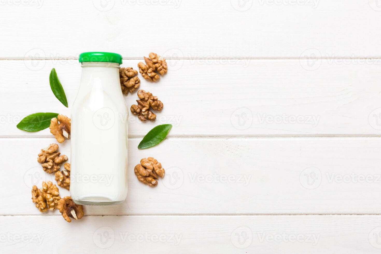 Vegan milk from Walnut bottles on wooden table, Vegetarian alternative food, clean eating concept. top view with copy space photo