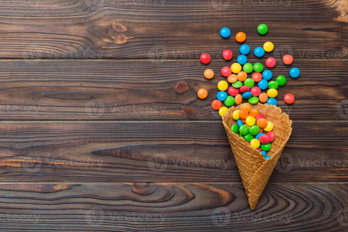 waffle cone full assorted traditional candies falling out on colored background copy space. Happy Holidays sale concept photo