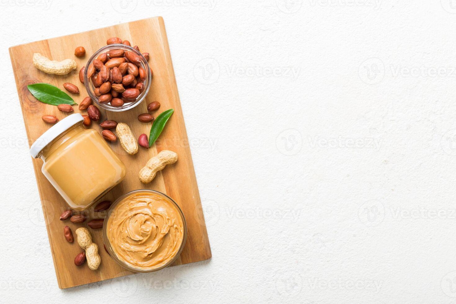 Bowl peanut butter and peanuts on table background. top view with copy space. Creamy peanut pasta in small bowl photo