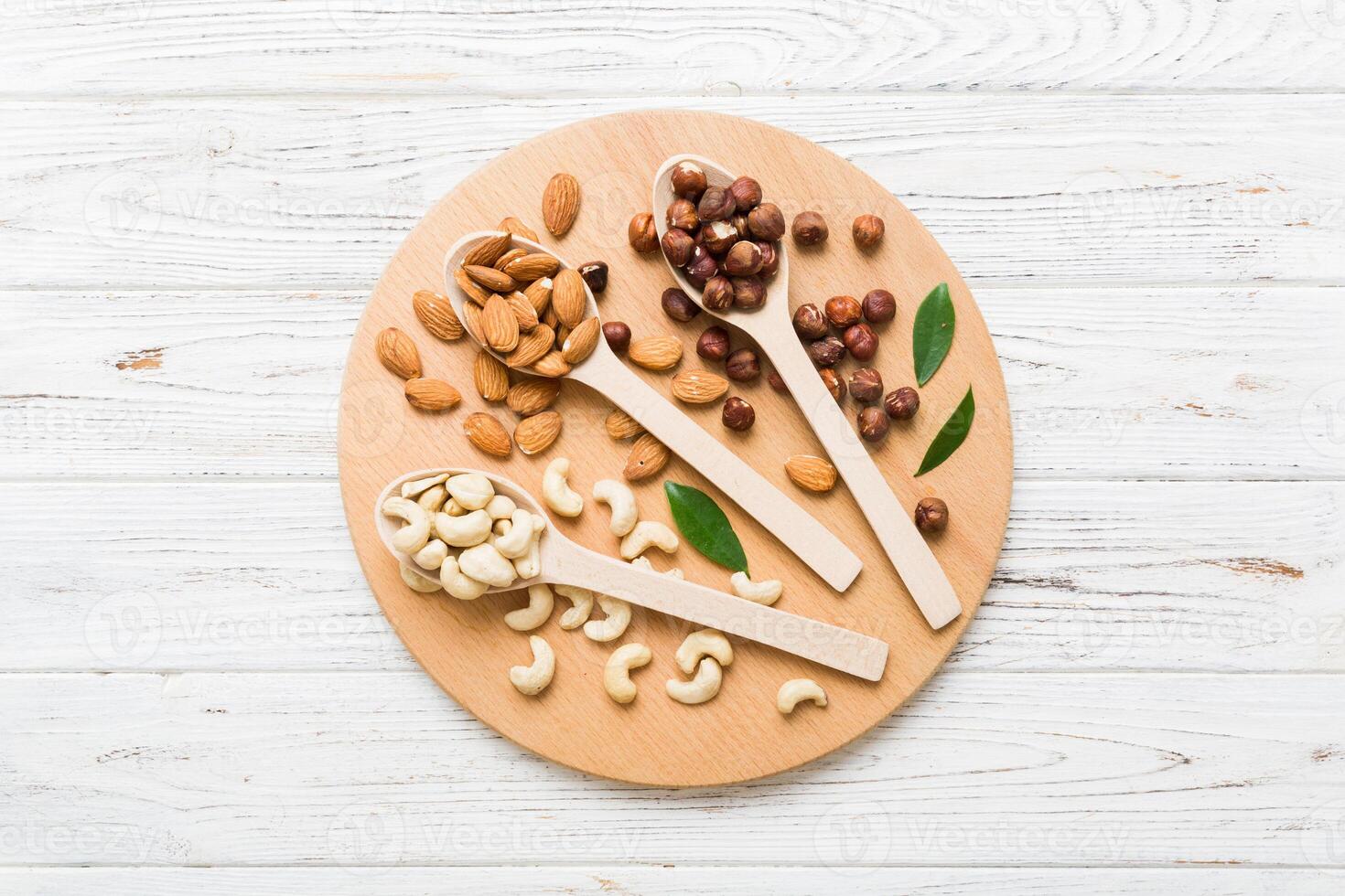 Assortment nuts in wooden spoon on colored table. Cashew, hazelnuts, walnuts, almonds. Mix of nuts Top view with copy space photo