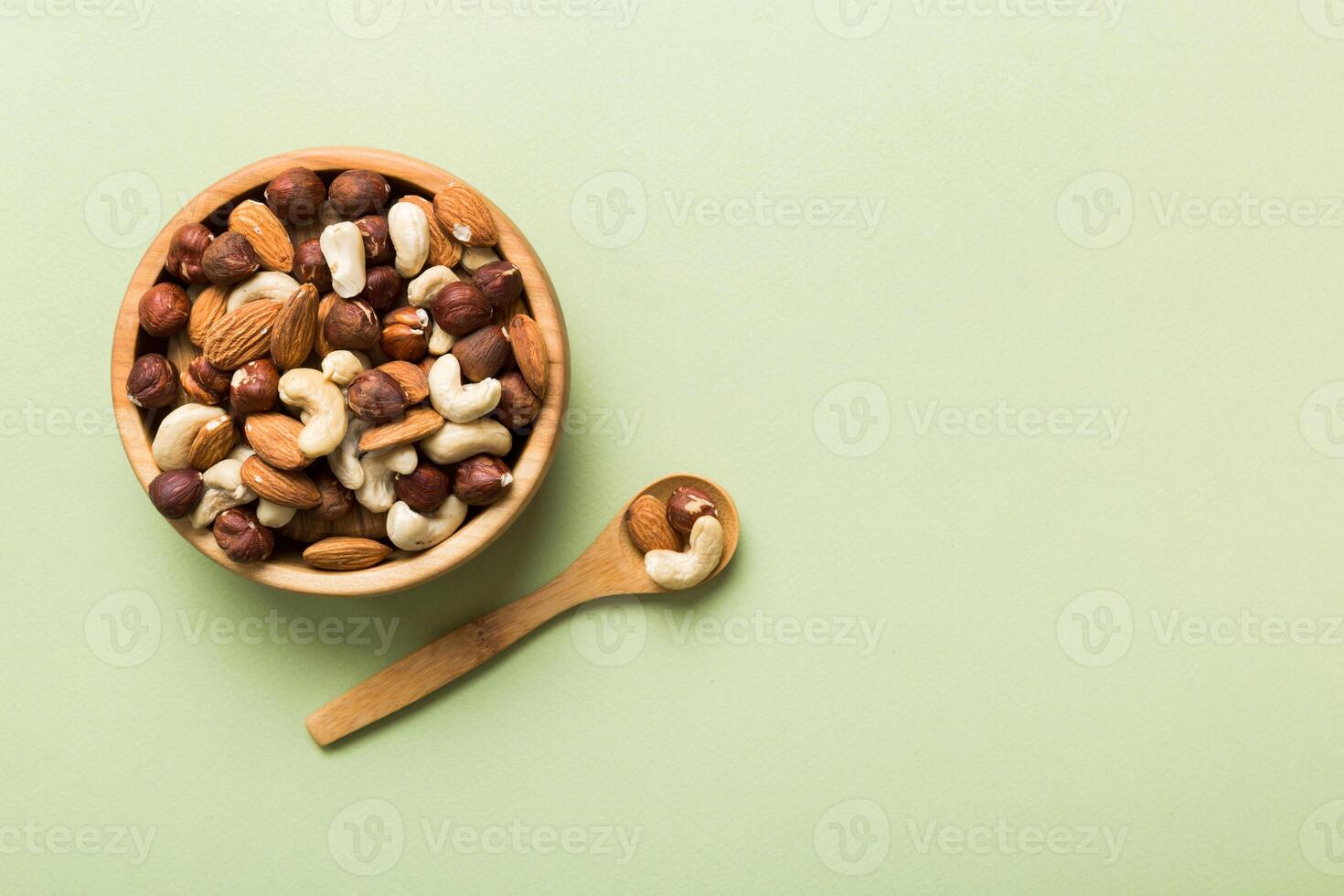 Assortment nuts in wooden bowl on colored table. Cashew, hazelnuts, walnuts, almonds. Mix of nuts Top view with copy space photo