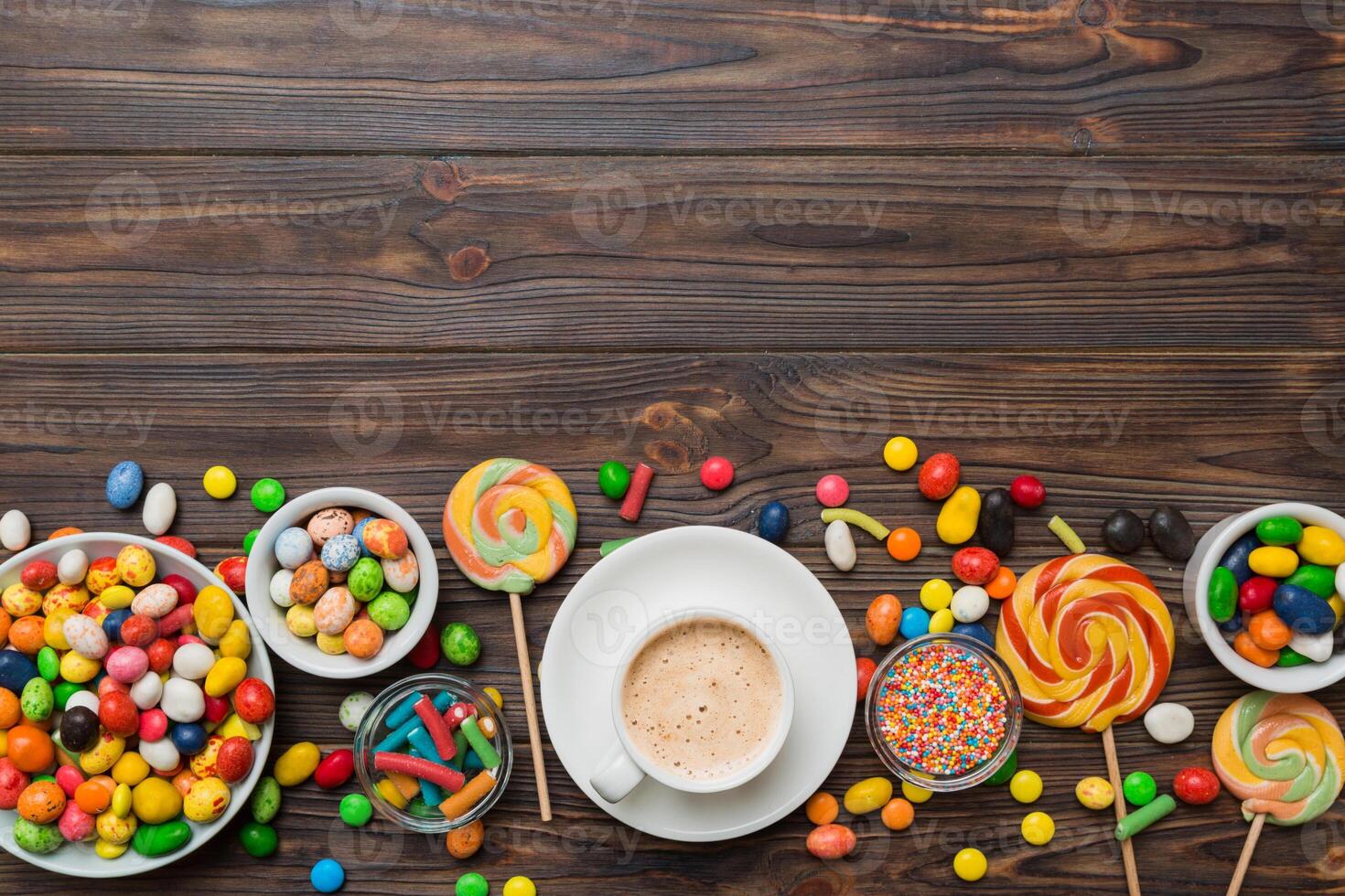 Coffee cup with chocolates and colored candy. Top view table background copy space photo