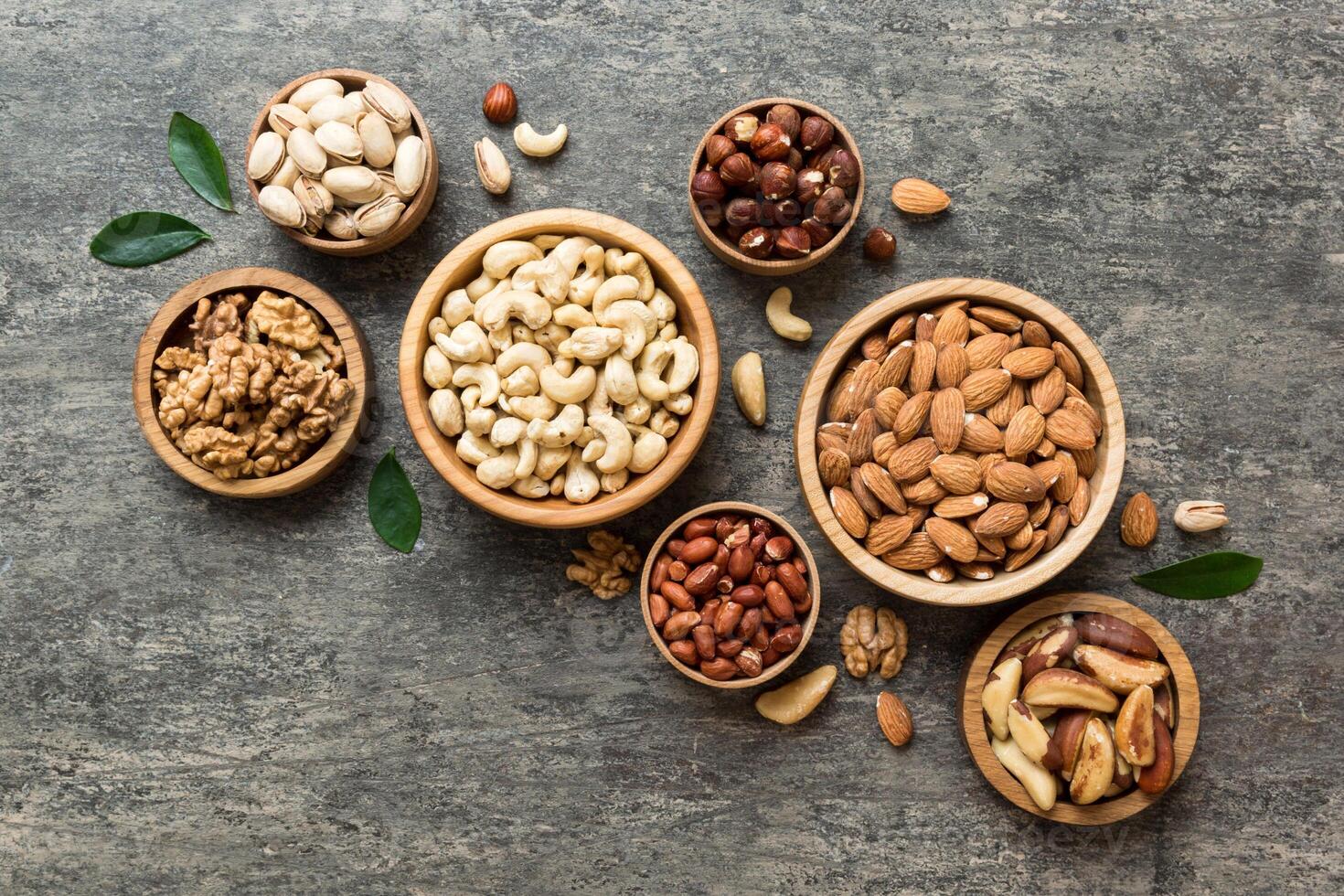 mixed nuts in wooden bowl. Mix of various nuts on colored background. pistachios, cashews, walnuts, peanuts and brazil nuts photo