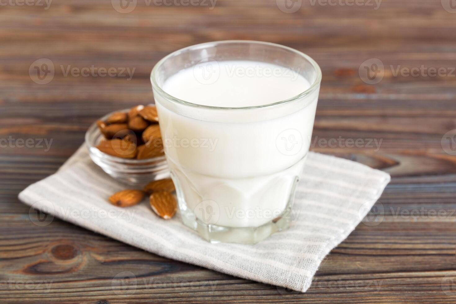Top view of the almond milk glass bottle with almond nuts on the colored table. top view vith copy space photo
