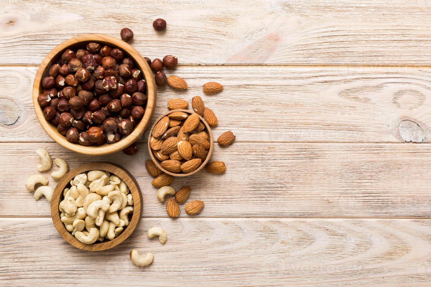 Assortment nuts wooden bowl colored table. Cashew, hazelnuts, walnuts, almonds. Mix nuts Top view copy space photo