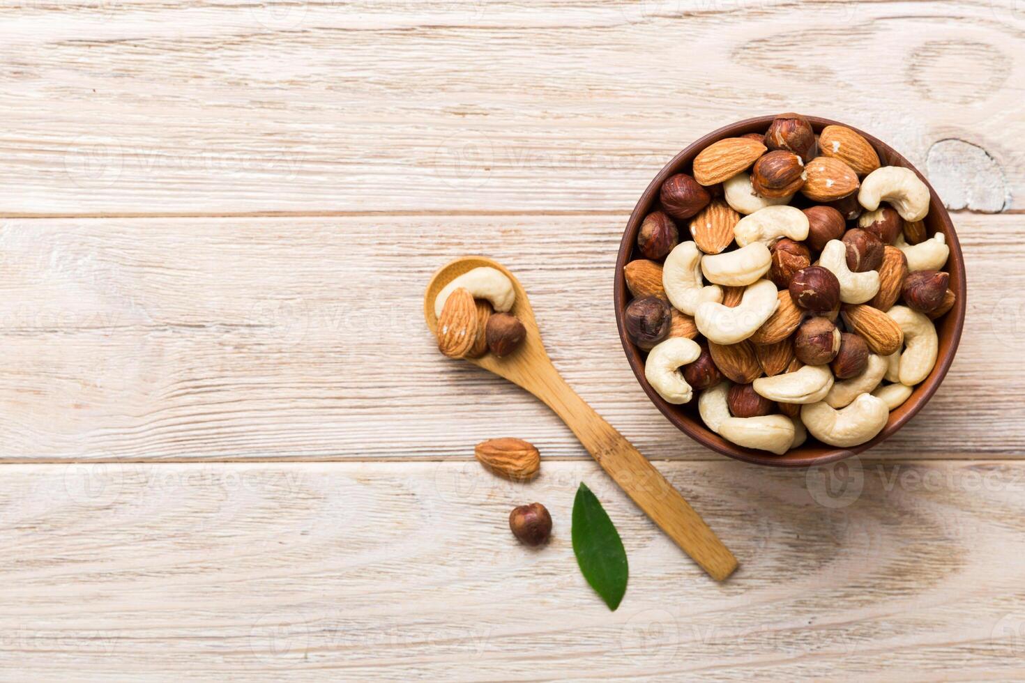 Assortment nuts in wooden bowl colored table. Cashew, hazelnuts, walnuts, almonds. Mix of nuts Top view with copy space photo