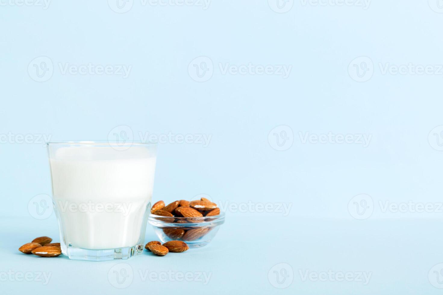 Top view the almond milk in the glass bottle with almond nuts on the colored table. top view vith copy space photo