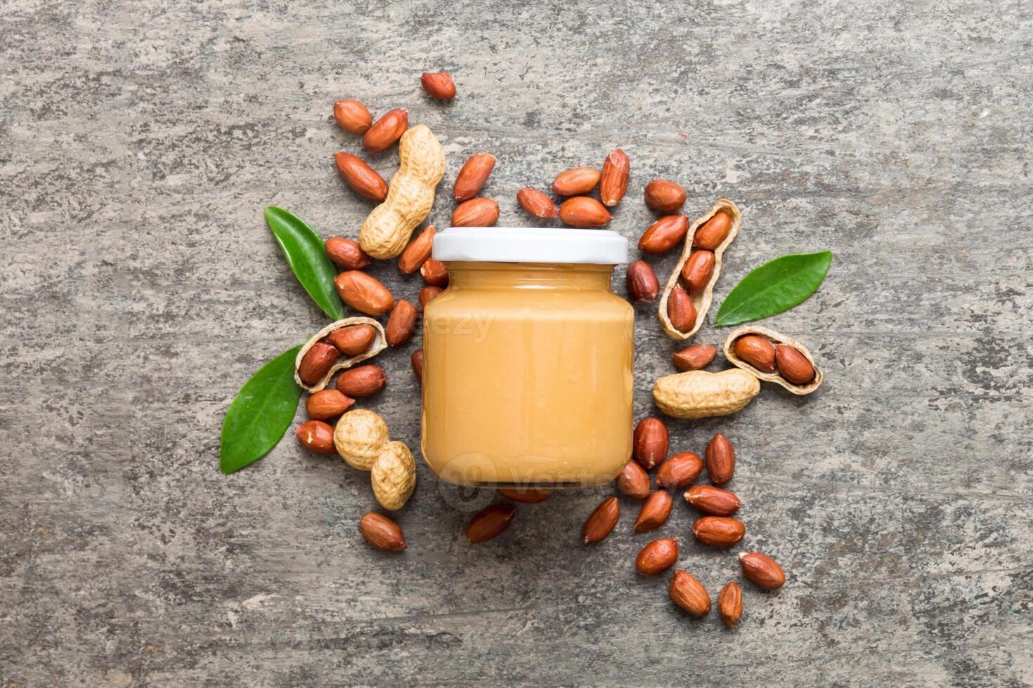 Bowl peanut butter and peanuts table background. top view with copy space. Creamy peanut pasta in small bowl photo