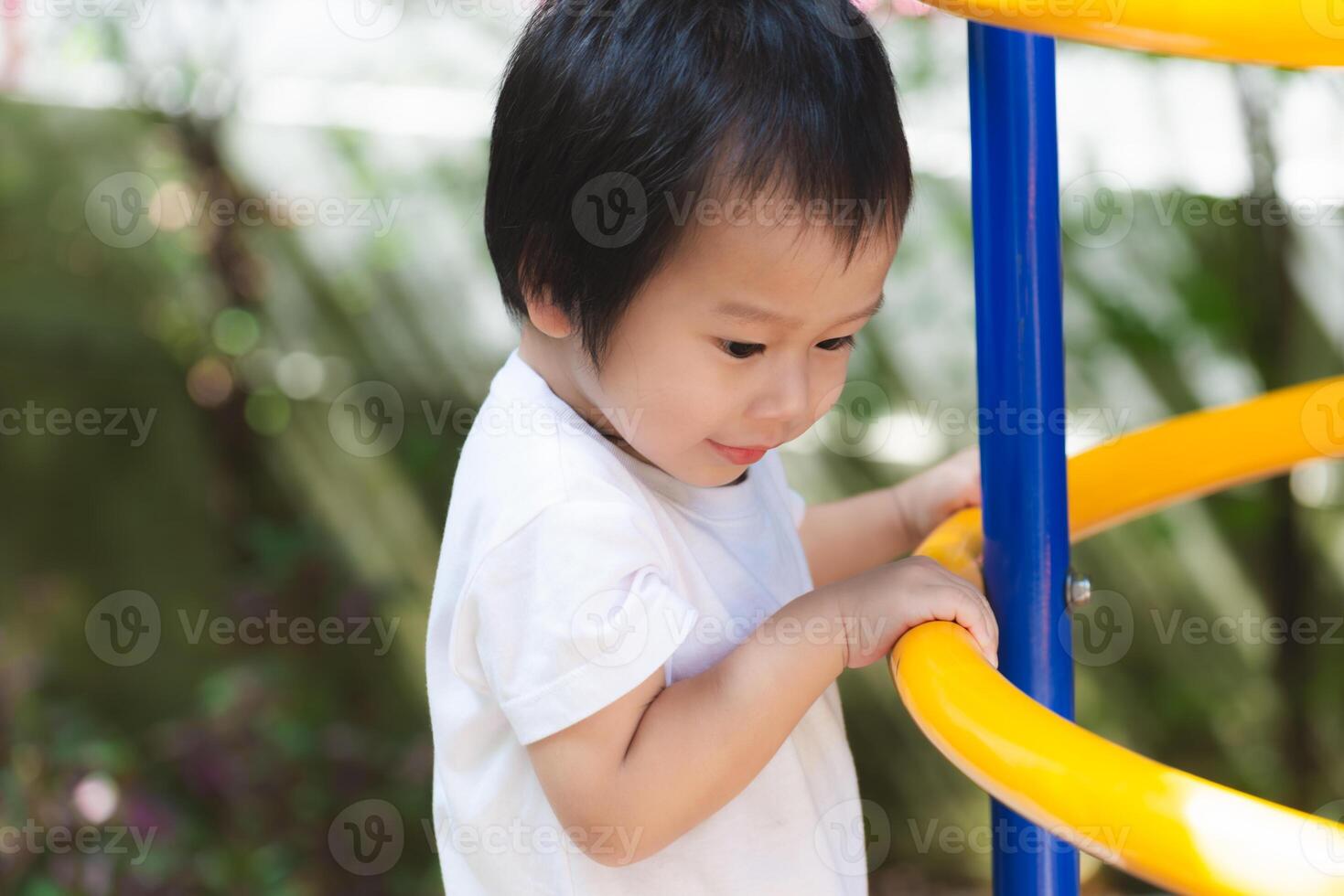 Child boy joyfully engages in outdoor play at a vibrant playground, surrounded by colorful structures, exuding pure happiness and youthful curiosity. Childhood Playtime. photo