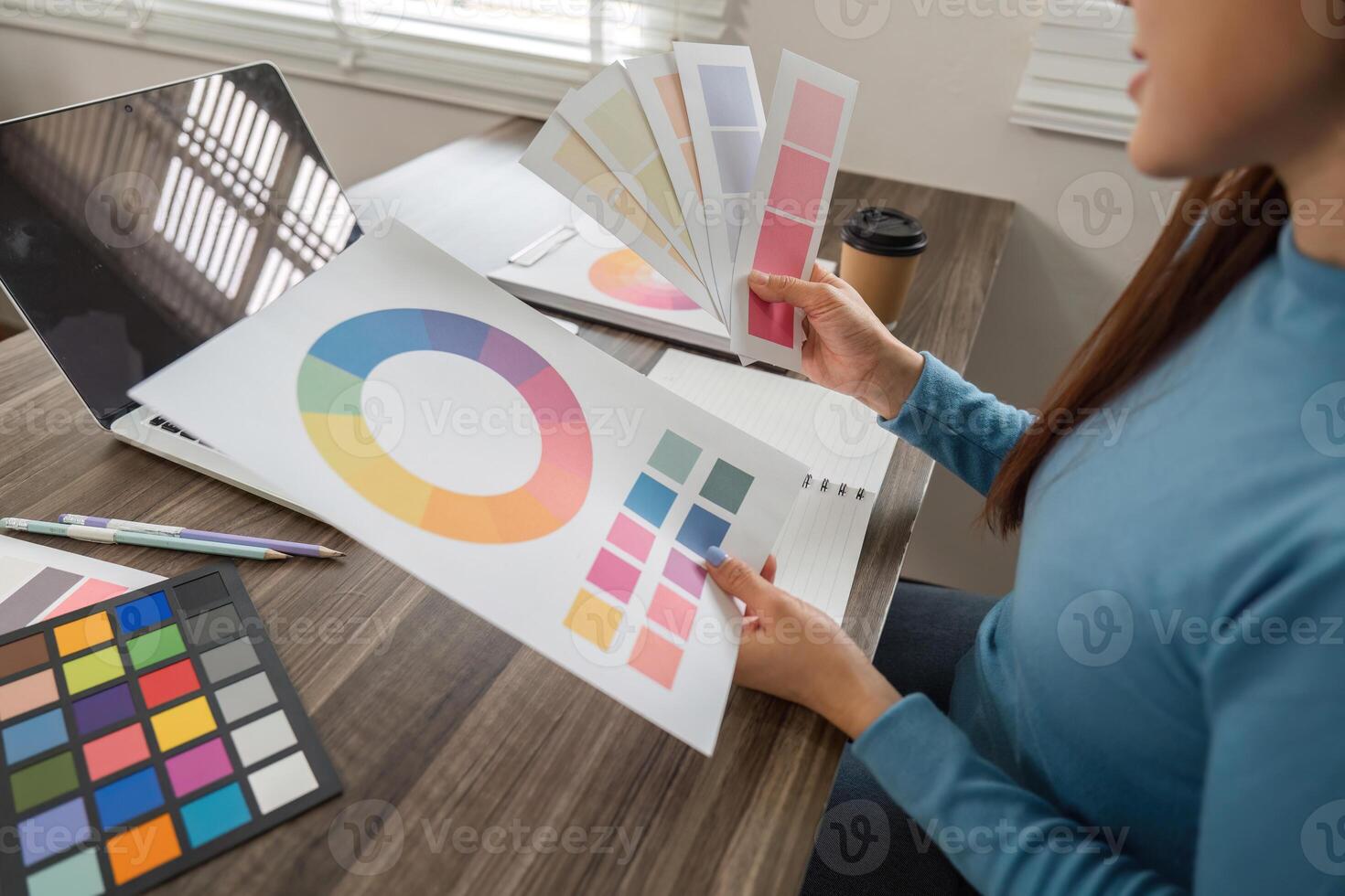 Color Evaluation and Design Creation. An artist analyzing color schemes and refining design elements at her desk. photo
