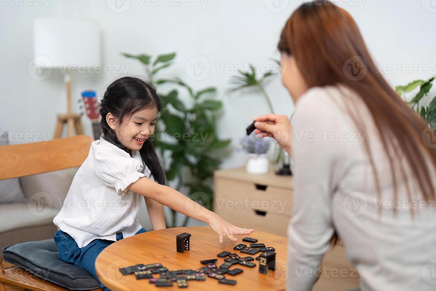 Game Night and Learning Experiences. A young girl eagerly playing a board game with her mother, sharing smiles and laughter. photo