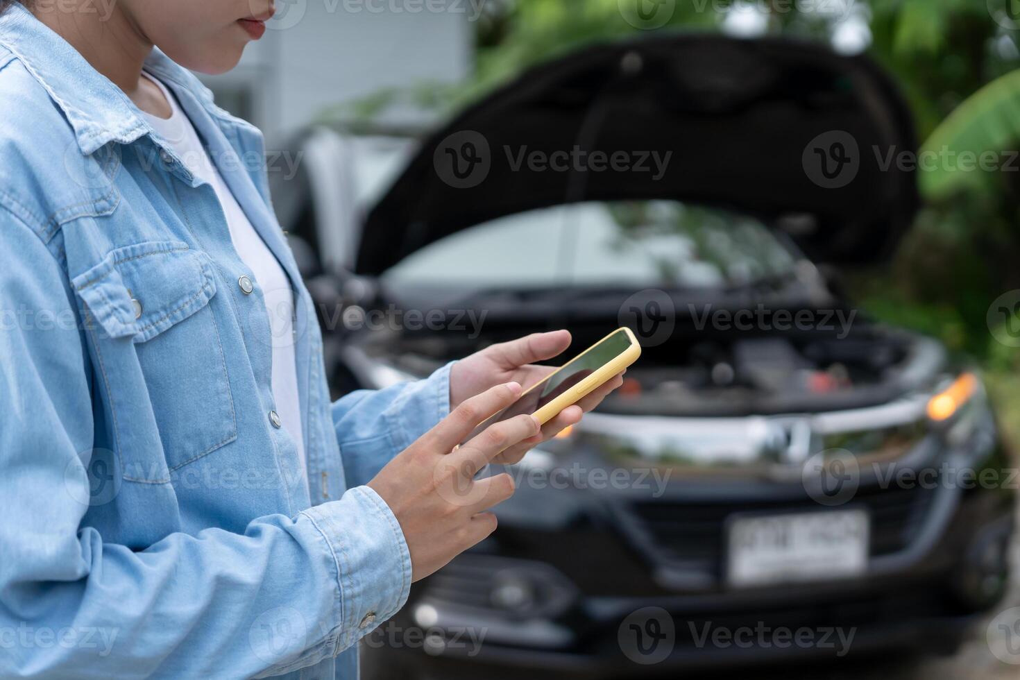 breakdown, broken car repair. Woman uses mobile phone check insurance premiums through application due to car accident . Find garage to get car fixed during country tour, waiting for help, emergency. photo