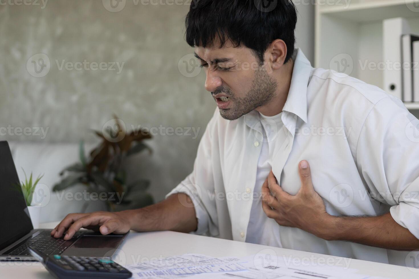 hand hold chest with heart attack symptoms, man working hard have chest pain caused by heart disease, leak, dilatation, enlarged coronary heart, press on the chest with a painful expression photo