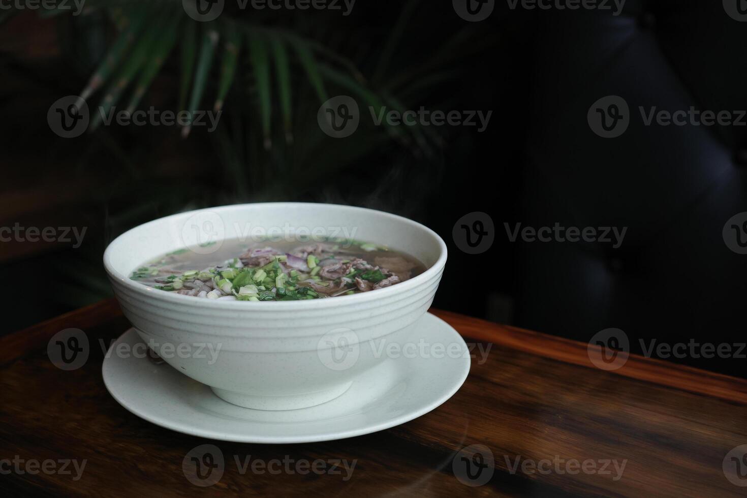 Traditional Vietnamese pho soup with beef slices served in a white ceramic bowl, copy space for text. Concept of authentic Asian cuisine, healthy food and comforting homemade meals. photo