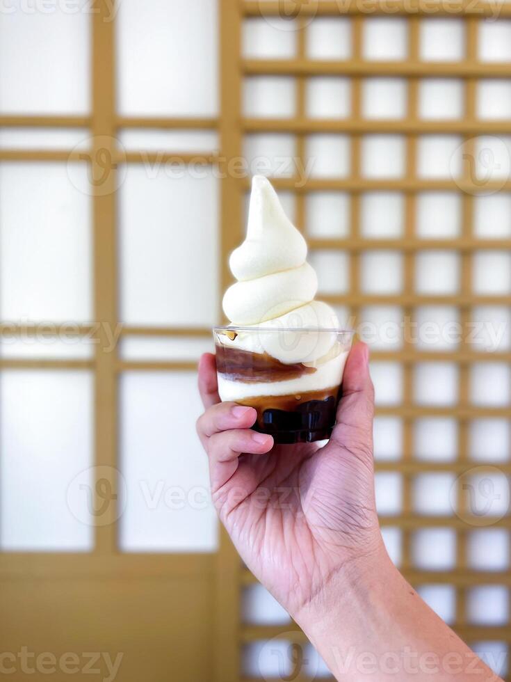 Hand holding a cup of Hokkaido fresh milk soft ice cream with pearls, a Japanese-style ice cream that is soft, fragrant, sweet, and refreshing. photo