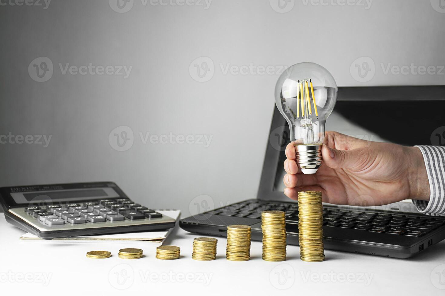 Business concept. A hand holds a lamp over coins on a light background. Business ideas, brainstorming photo