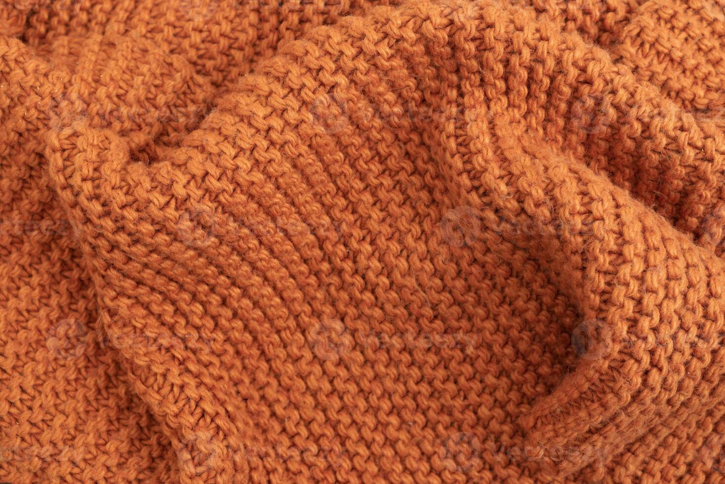 Orange knitted fabric texture abstract background. A slightly crumpled knitted blanket made of woolen threads. Winter or autumn warm background. photo