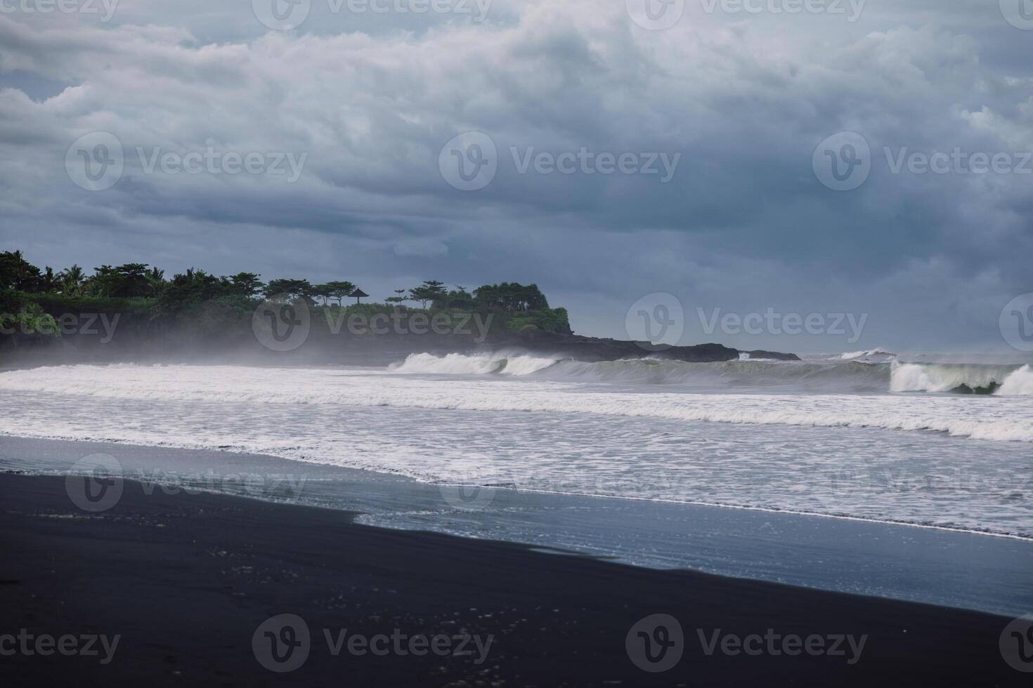 Volcanic black sandy beach with ocean waves in Bali. Beach and dark sky photo