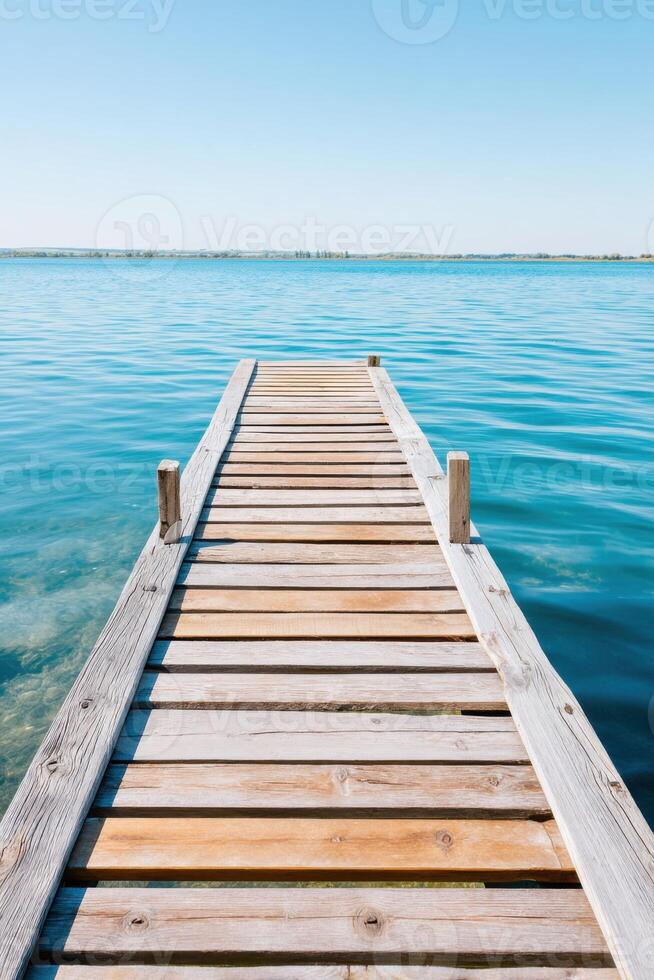 Wooden dock extending over calm blue water under a clear sky, inviting relaxation and tranquility, perfect for nature lovers and outdoor enthusiasts seeking peaceful moments photo