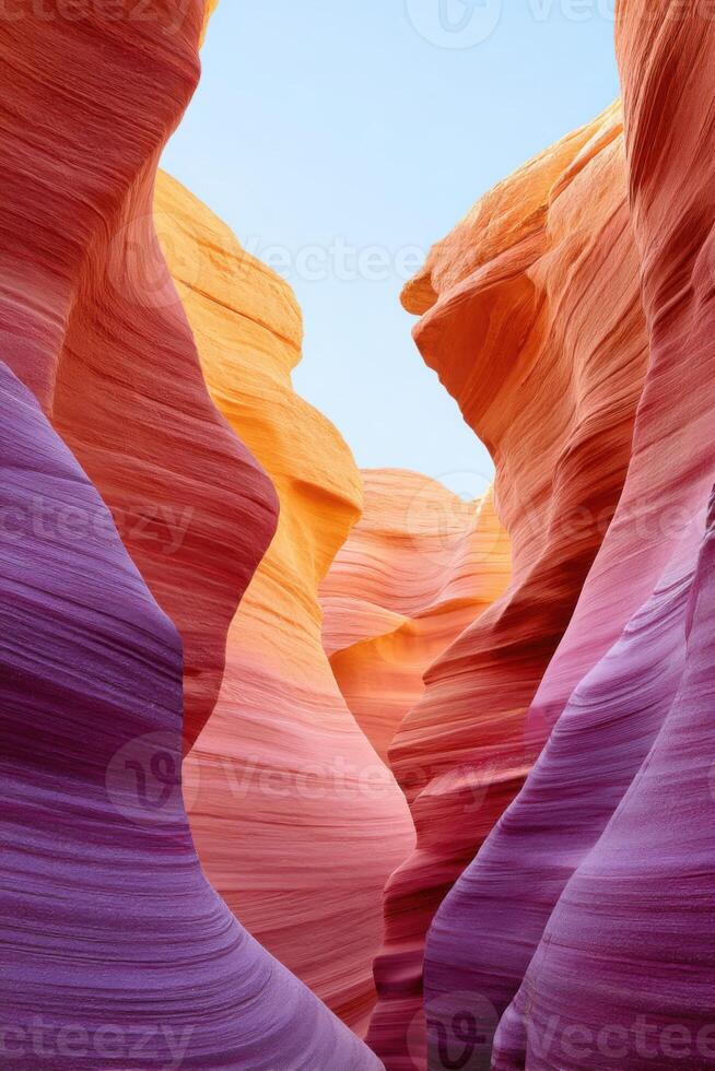 Colorful sandstone formations create a stunning visual display in a narrow canyon, showcasing vibrant hues of orange, purple, and pink under a clear blue sky with copy space photo