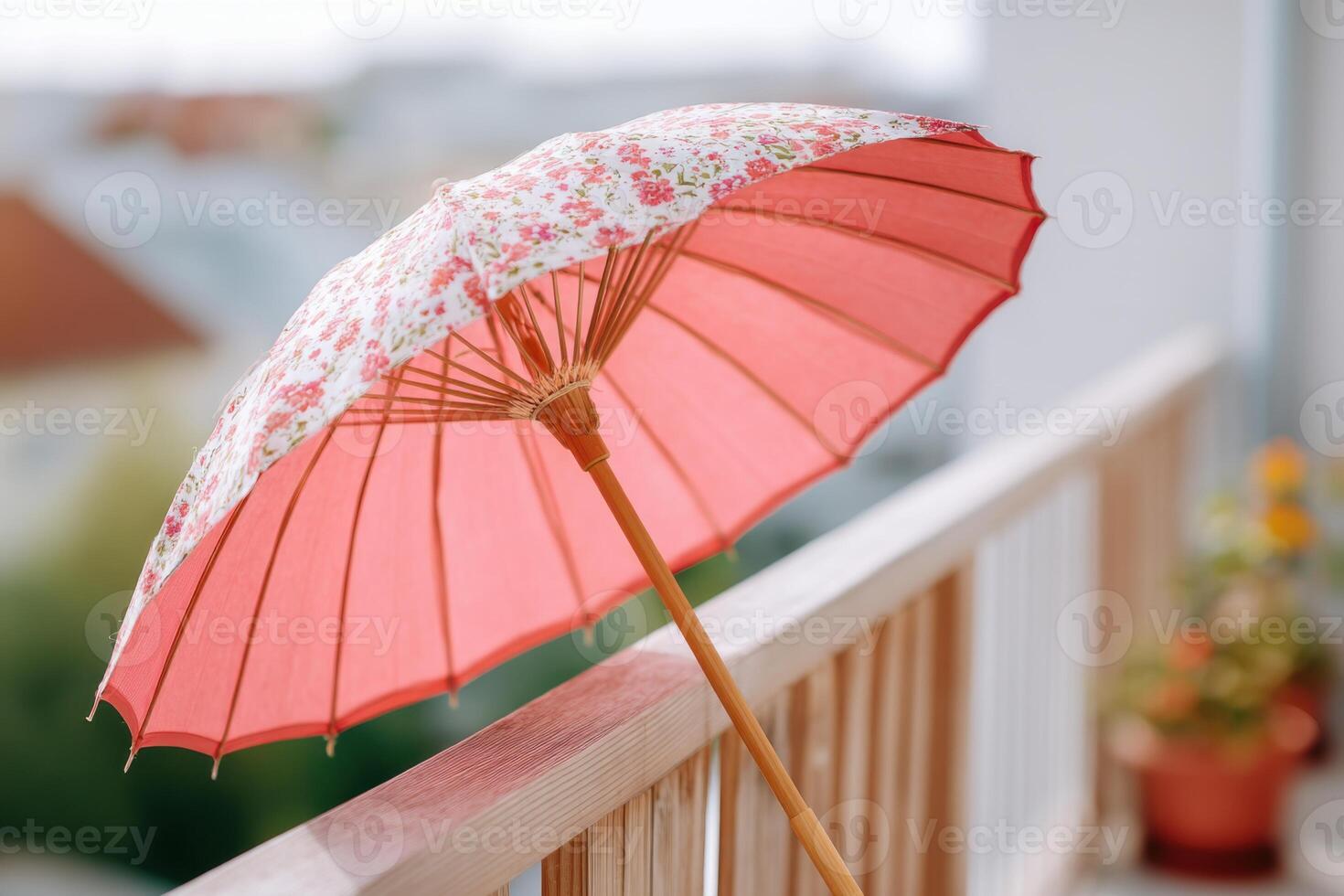 Decorative pink parasol with floral patterns rests on a wooden railing, providing shade and enhancing outdoor ambiance in a serene garden setting with soft colors photo