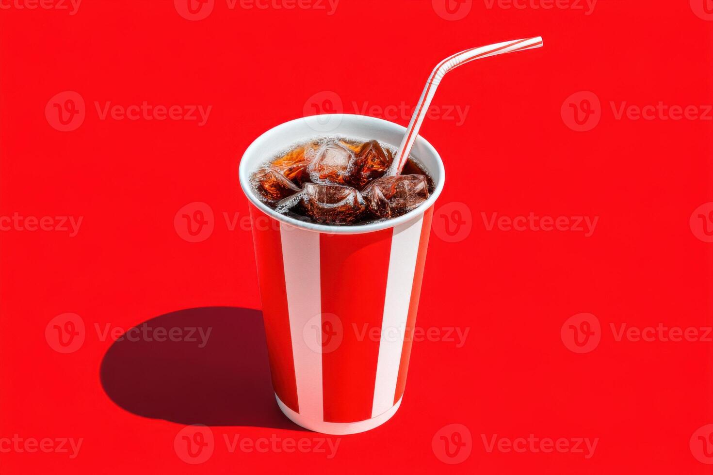 Refreshing beverage in a classic striped cup filled with ice cubes and a straw, set against a vibrant red background, evoking a sense of summer enjoyment and nostalgia photo