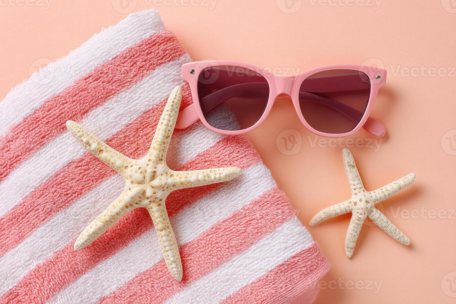 Pink sunglasses resting on a striped beach towel beside two starfish, creating a vibrant summer scene that evokes relaxation and coastal vibes photo