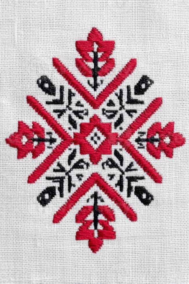 Ukrainian cross-stitch embroidery pattern featuring intricate floral and geometric designs in red and black on a light fabric background, showcasing traditional craftsmanship and cultural artistry photo