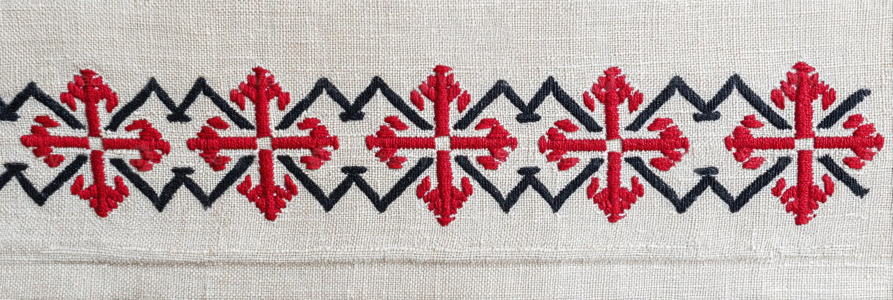 Romanian traditional embroidery featuring intricate red and black patterns on a natural fabric background, showcasing cultural artistry and craftsmanship in textile design photo