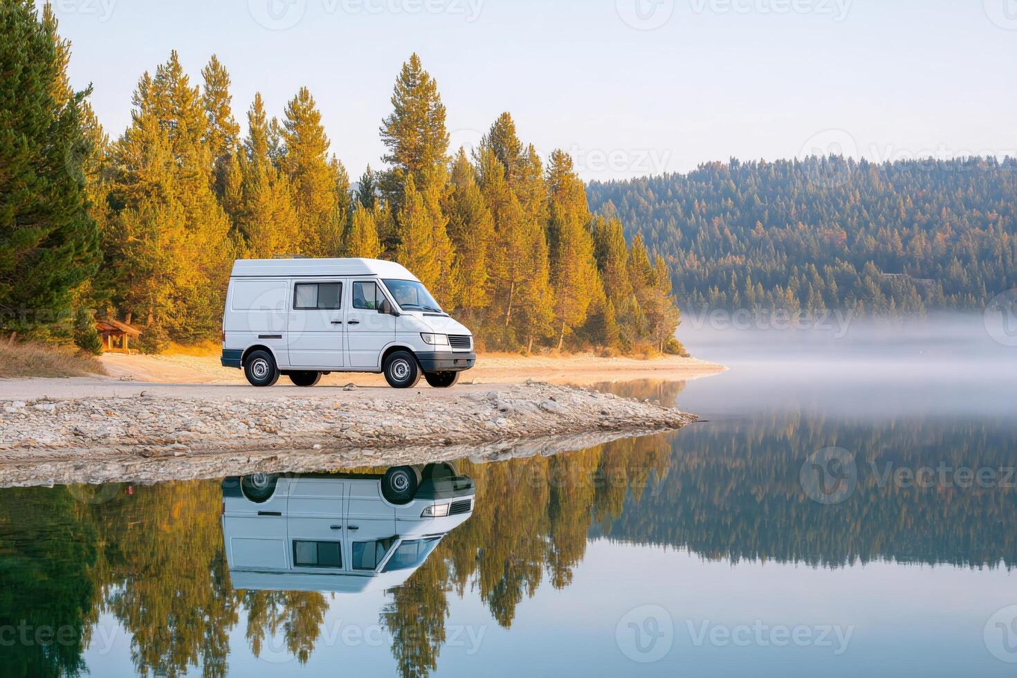 White camper van parked by serene lake surrounded by lush green trees, reflecting in calm water, showcasing peaceful outdoor adventure and exploration photo