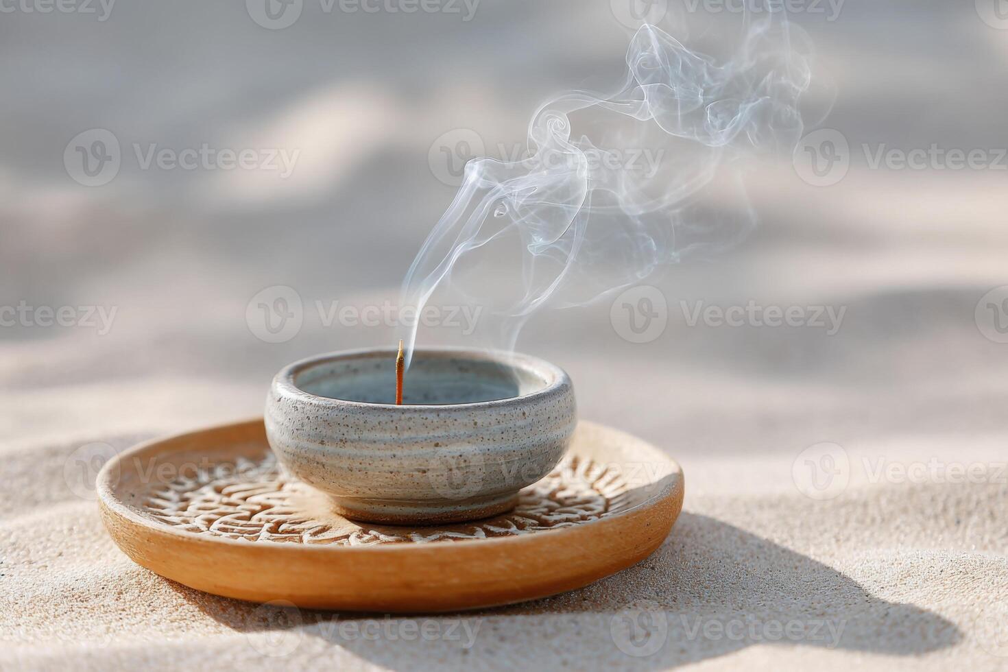 Incense holder with smoke rising, placed on a decorative wooden plate, resting on soft sand, creating a serene atmosphere for relaxation and meditation photo