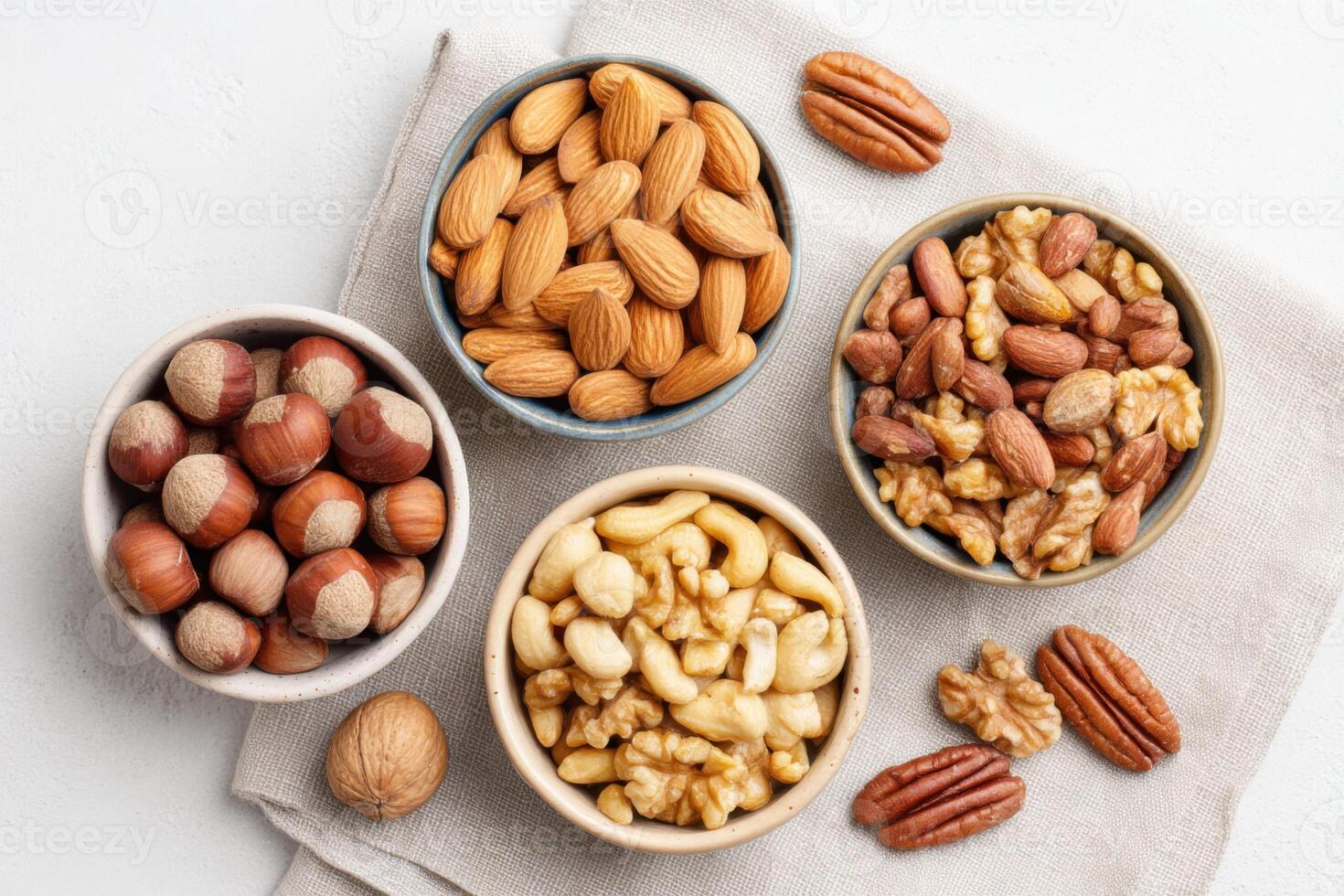 Assorted nuts in bowls on a beige cloth, featuring almonds, hazelnuts, walnuts, and pecans, showcasing healthy snacks and natural textures for culinary inspiration photo