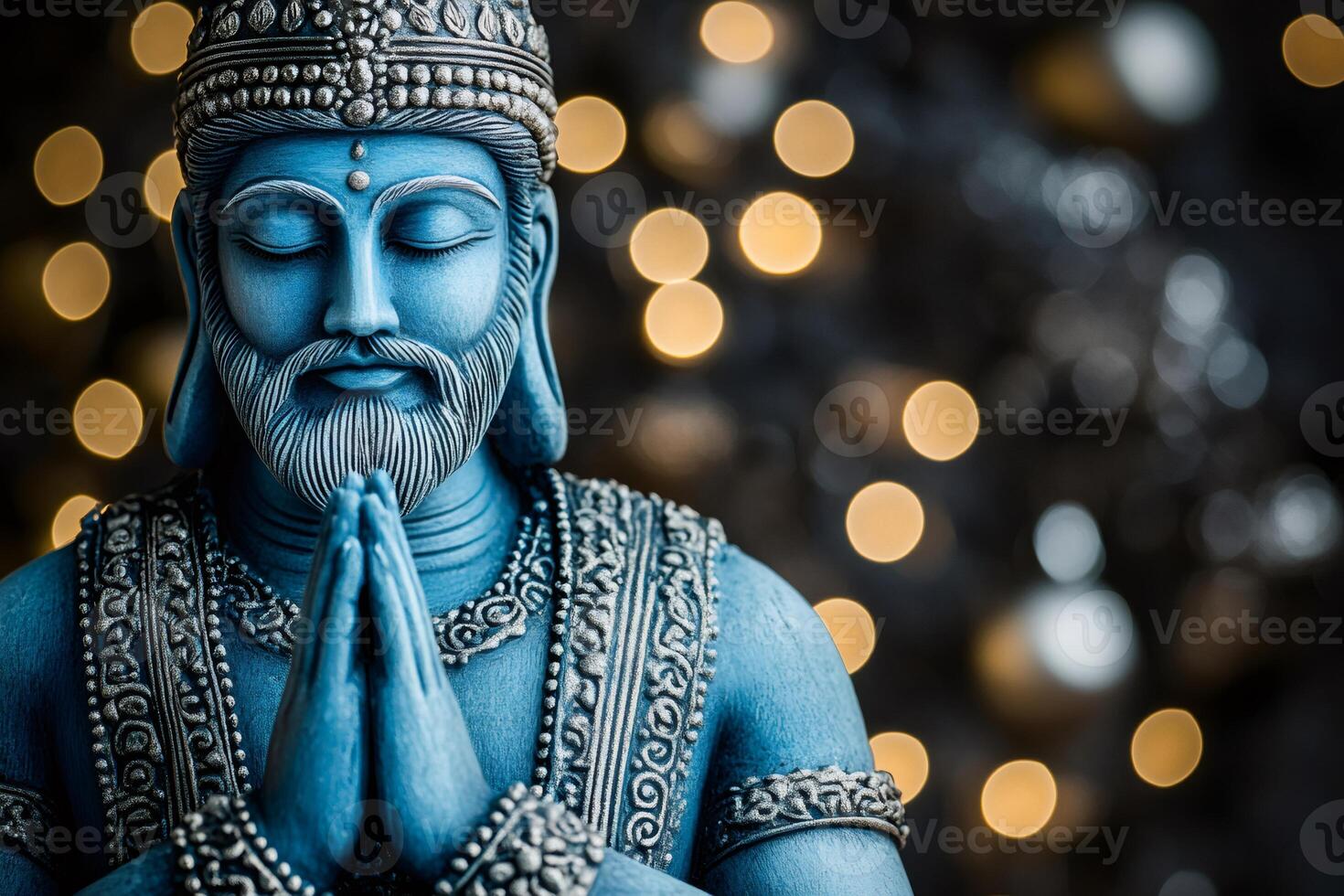 Blue statue of a meditating deity joining hands in prayer with bokeh lights photo