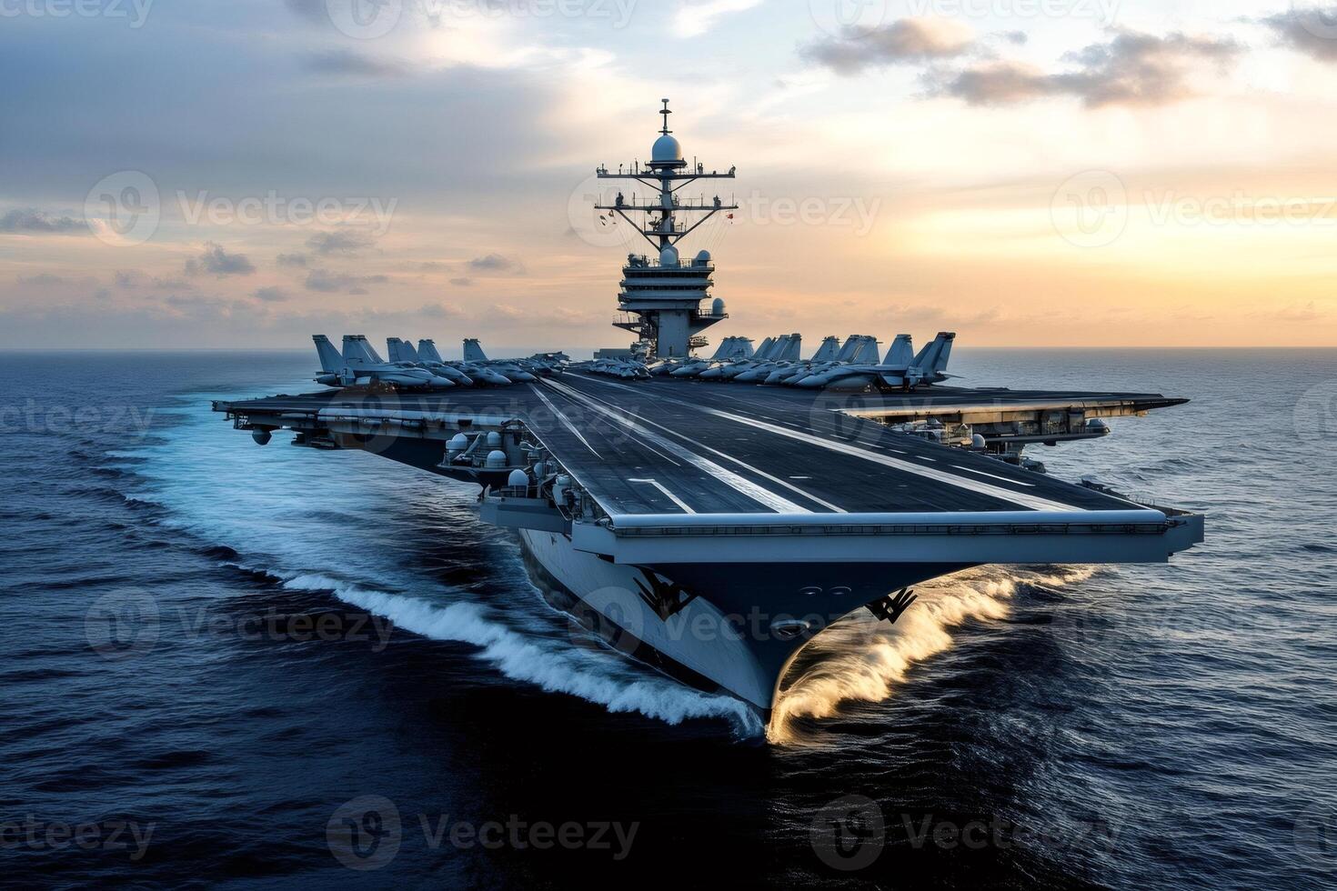 Powerful aircraft carrier cruising on the ocean at sunset with fighter jets on deck photo