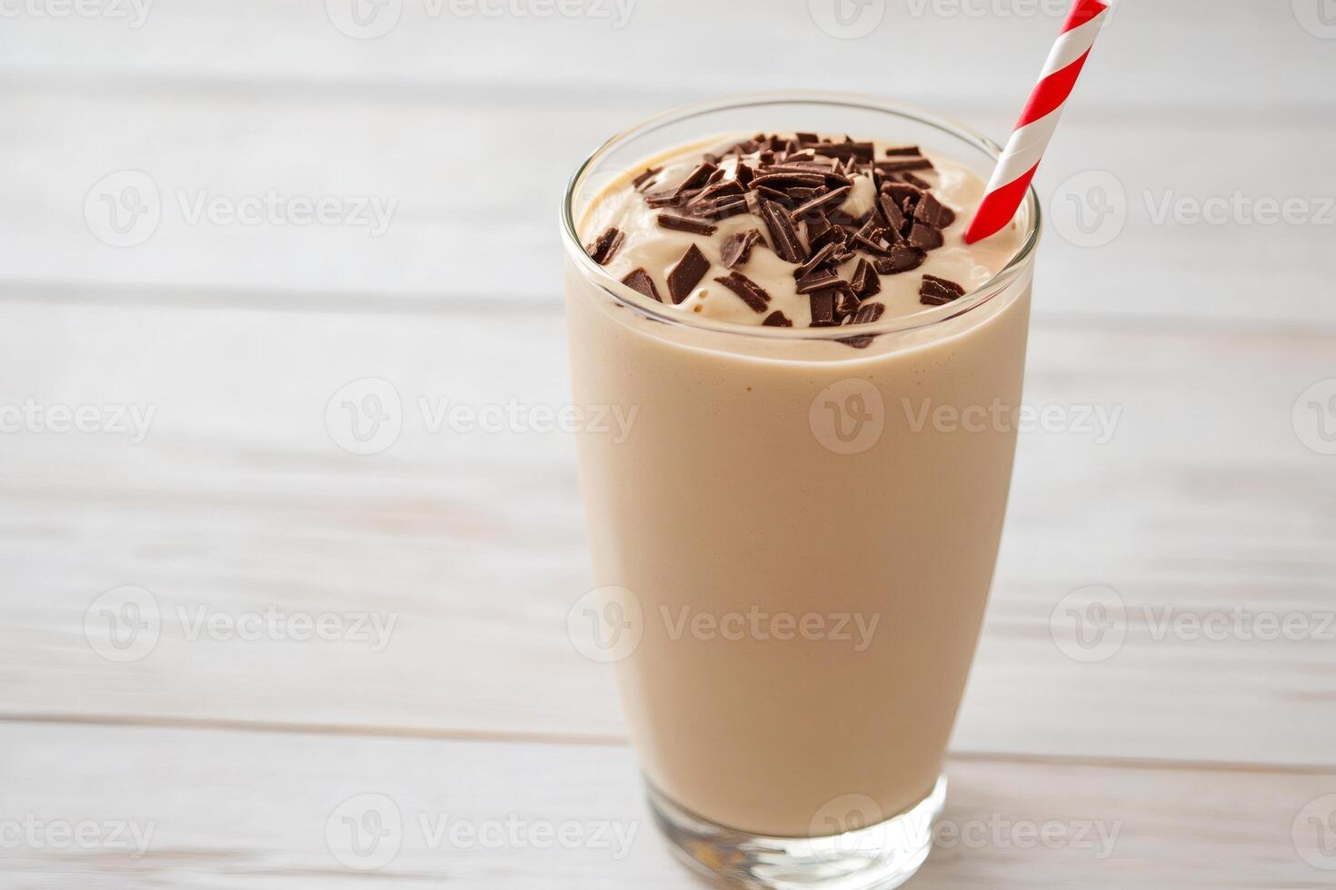 Chocolate milkshake decorated with chocolate shavings and red and white straw on white table photo