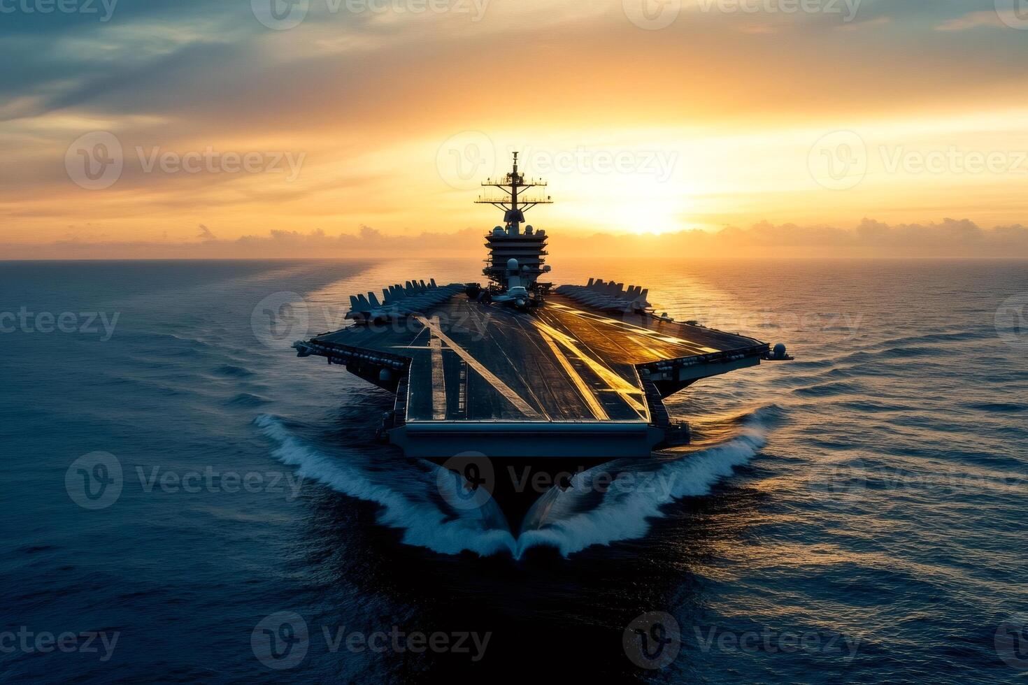 Aircraft carrier sailing on the ocean at sunset with fighter jets parked on deck photo