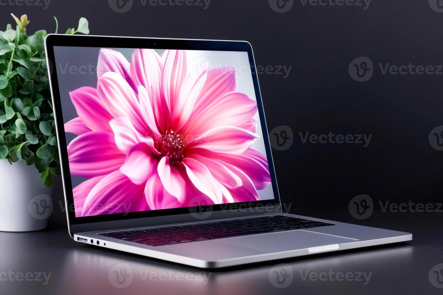 Modern silver laptop displaying a vibrant pink flower on a dark desk photo