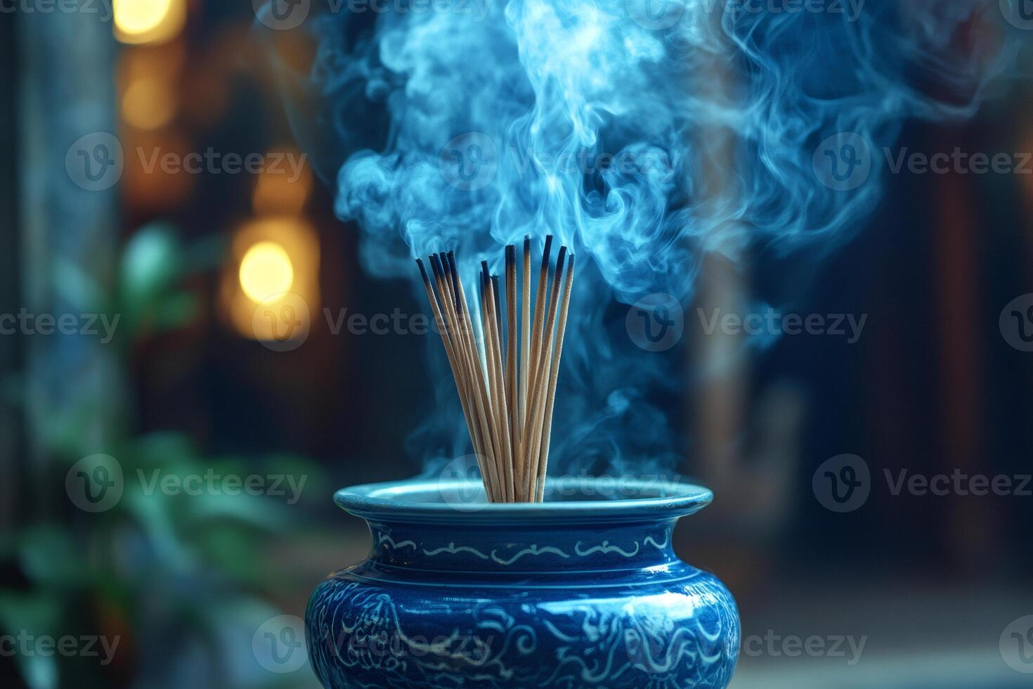 Incense burning, creating a mystical blue smoke in a decorated pot photo