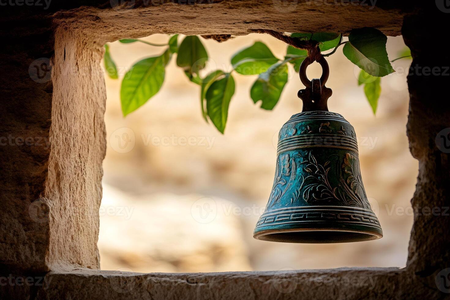 Green metal bell hanging from stone wall with vine growing around it photo