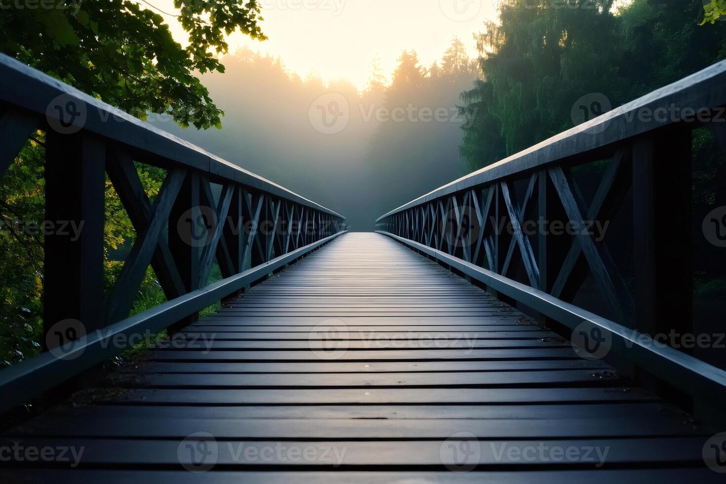 Wooden bridge leading into misty forest at sunrise photo
